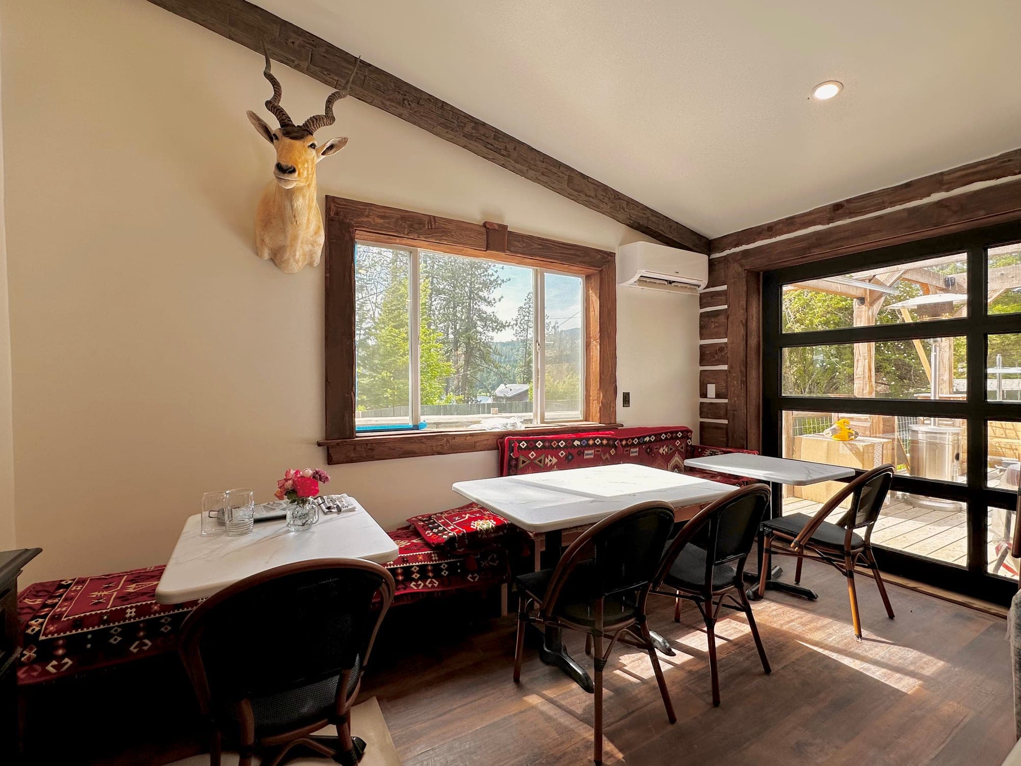 Red's Tavern dining room with kilim-cushioned banquette, antelope mount, and view to the deck at Watson's Lakefront Resort