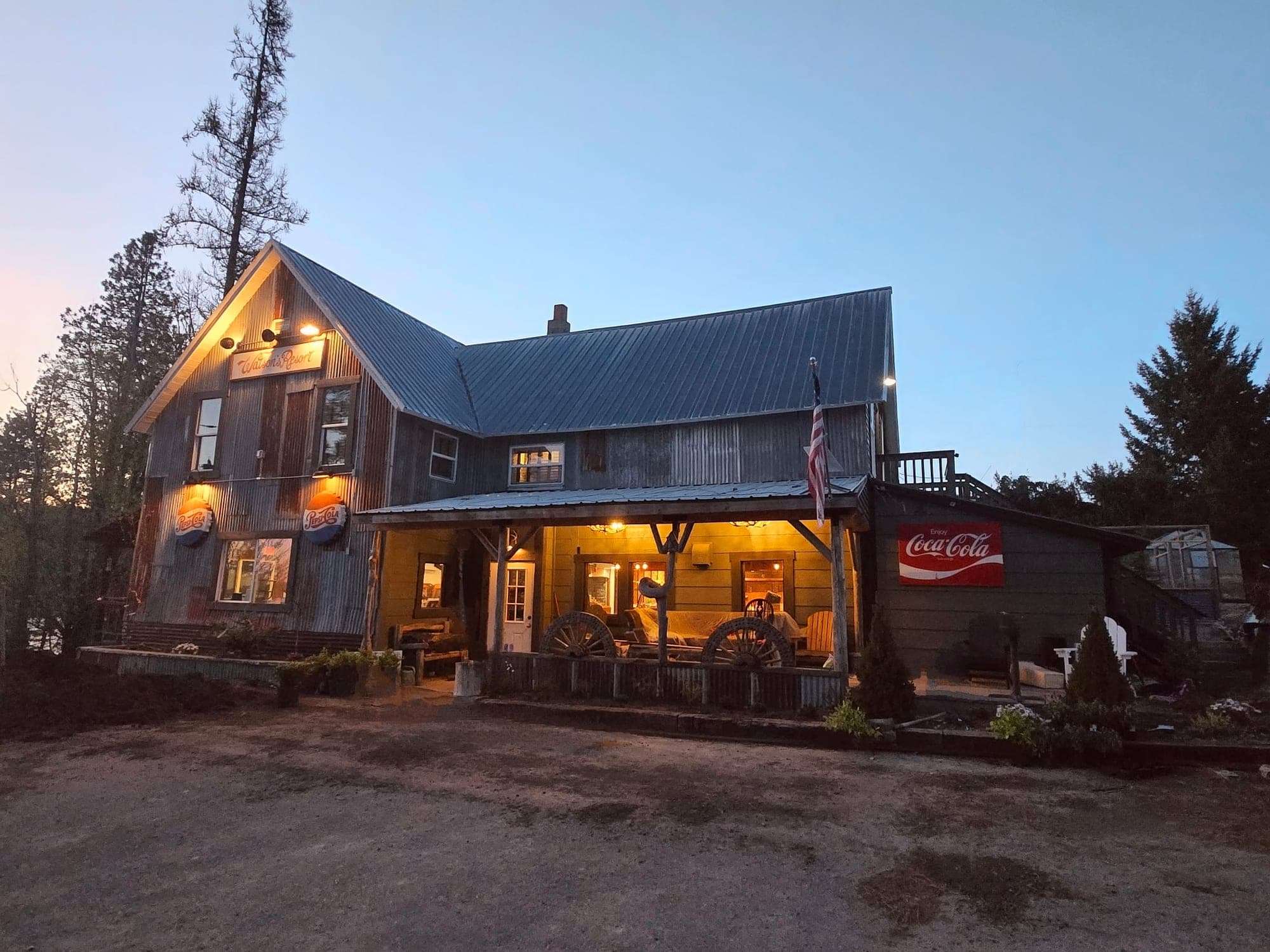Red's Tavern at Watson's Lakefront Resort glowing at twilight with vintage Coca-Cola sign and covered porch