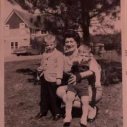 Sepia-toned vintage portrait of a woman with two young boys in front of a lodge building on the Watson's property