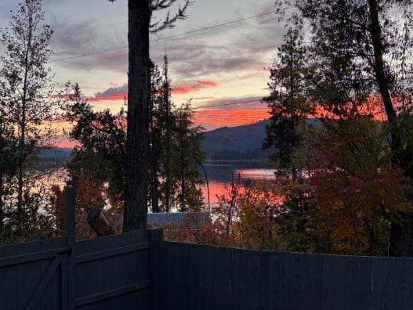 Lawn and split-rail fence overlooking Rose Lake at golden hour at Watson's Lakefront Resort